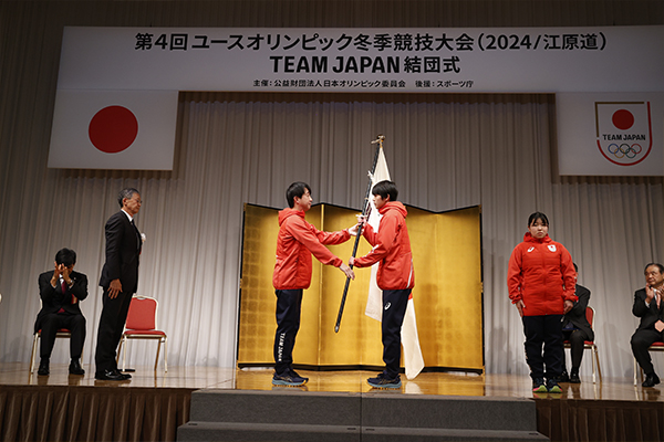 原田雅彦団長から藤井海斗旗手へと団旗が授与された（写真：フォート・キシモト）