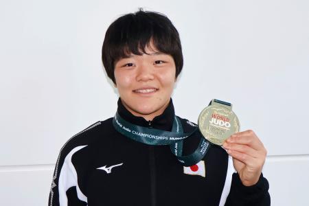 柔道の世界選手権から帰国し、女子６３キロ級で獲得した金メダルを手にポーズをとる嘉重春樺＝１８日、羽田空港