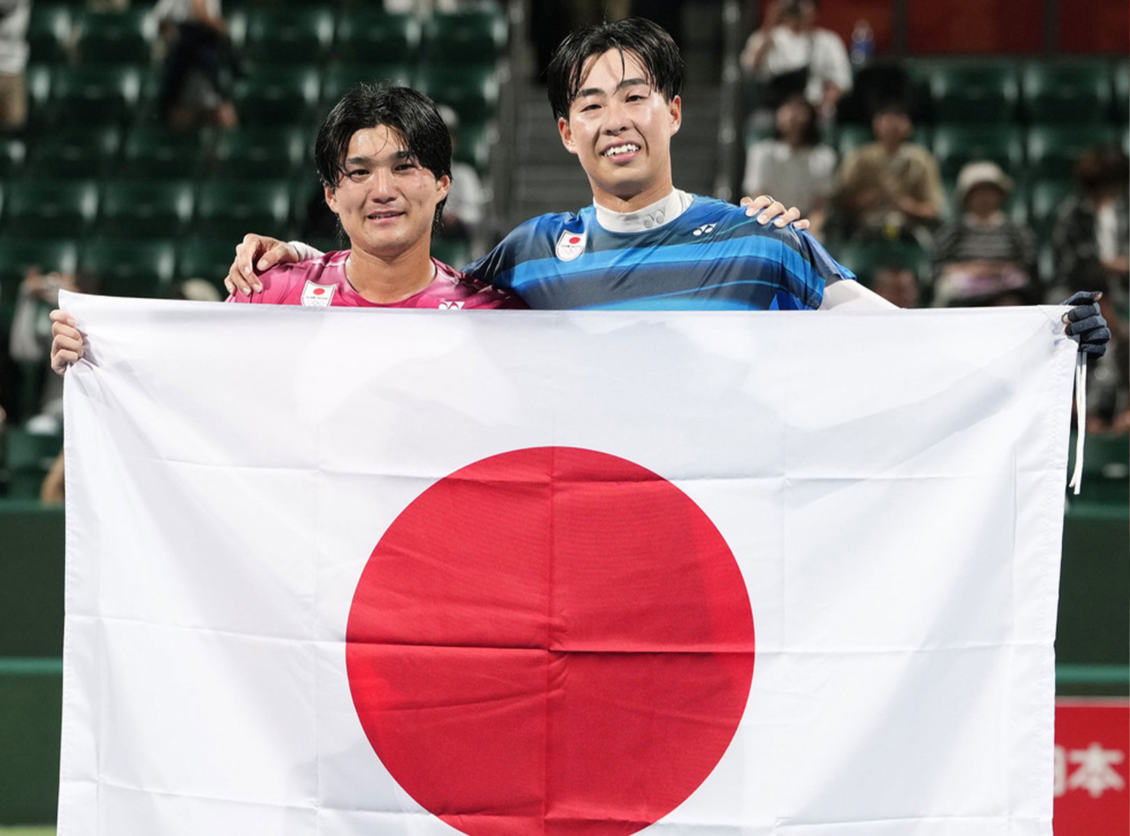 日の丸掲げる上松と黒坂（写真：共同）
