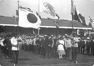 1920年、第7回アントワープ大会の開会式。日本とイタリアの国旗の間に五輪マークの旗が見える。